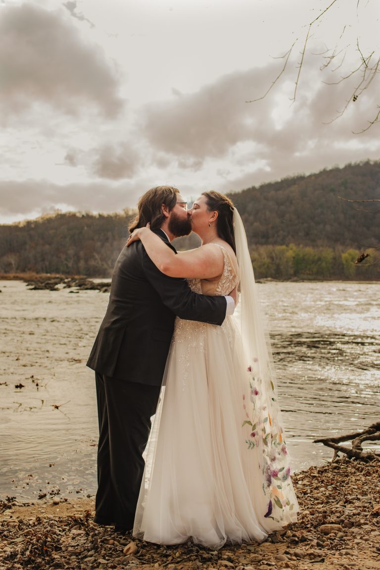 Bride and Groom kiss infront of river