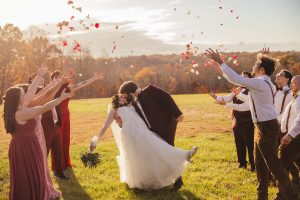 The wedding party tosses flowers on the Bride and Groom
