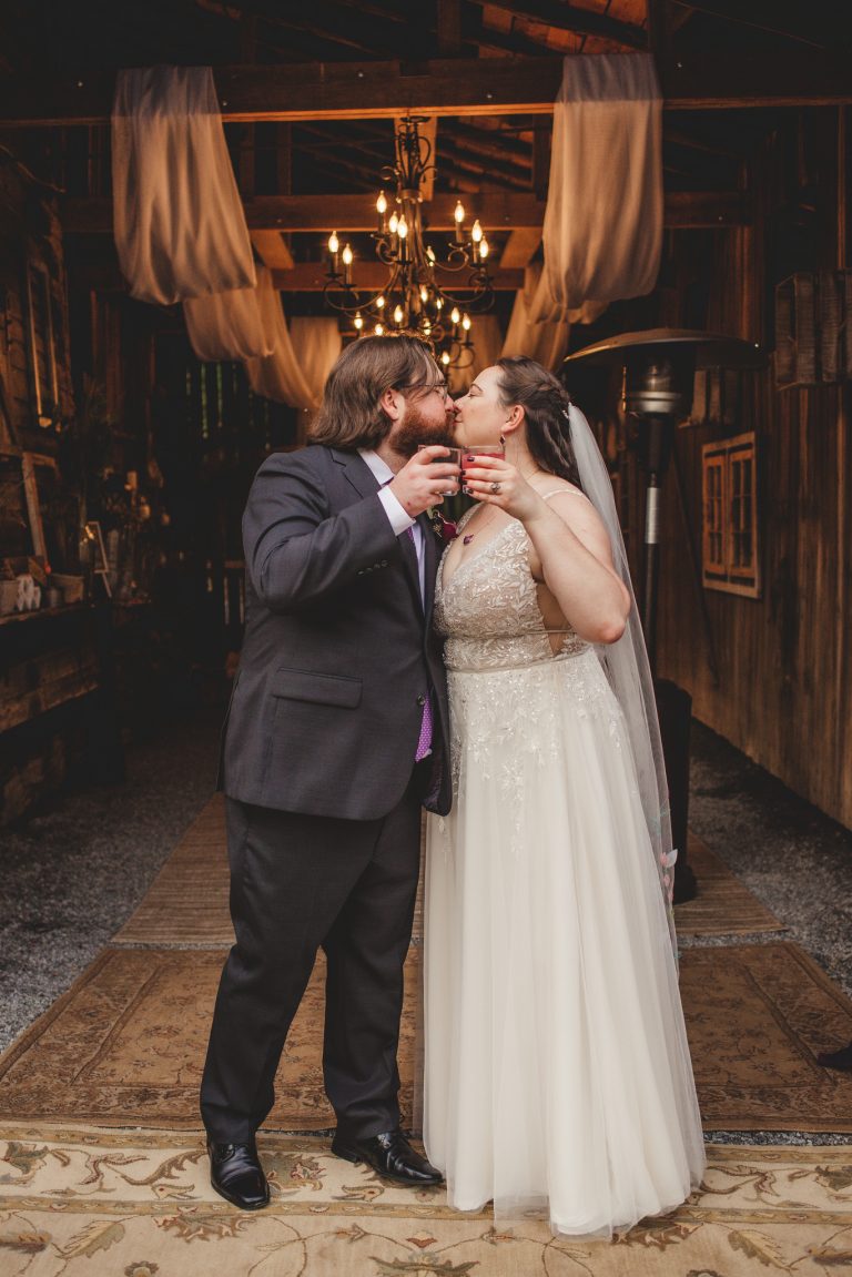 Bride and Groom kiss while holding glasses